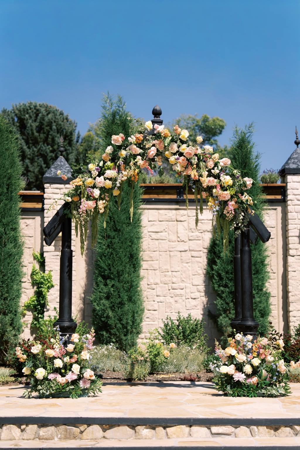 Outdoor ceremony arch surrounded by flowers